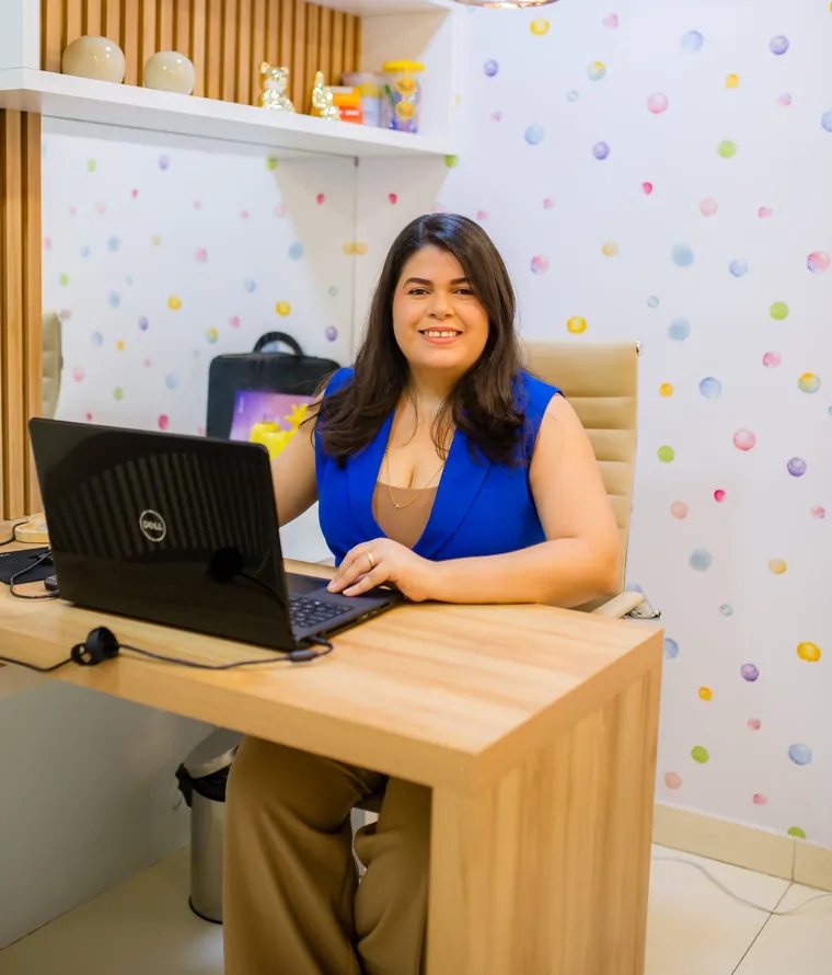 Dra. Hanna Emile no consultório infantil, com parede de bolinhas coloridas