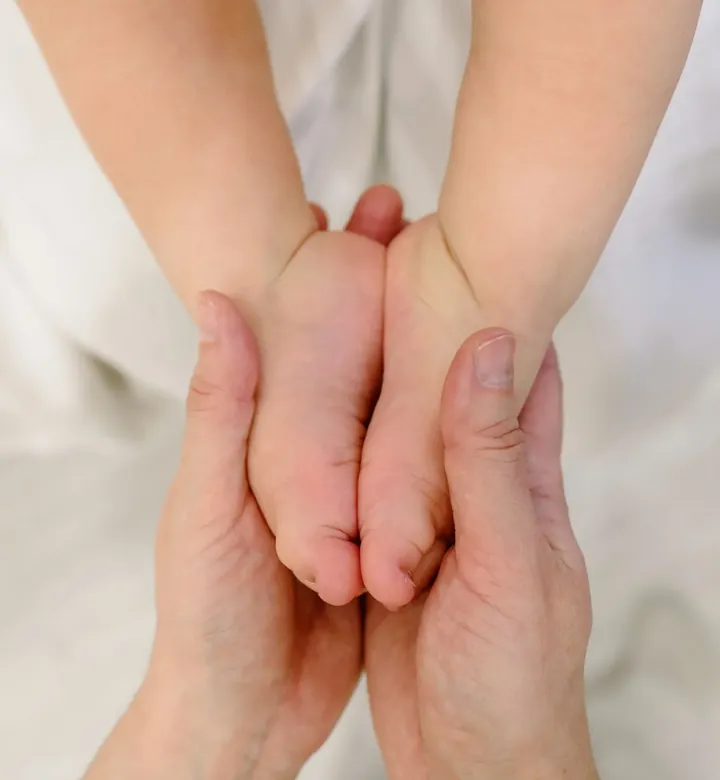 Mãos de adulto segurando os pés de um bebê